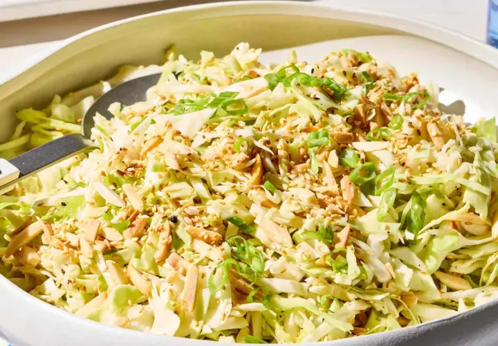 A refreshing Japanese cabbage recipe salad, topped with toasted almonds, sesame seeds, and green onions, served in a white bowl.