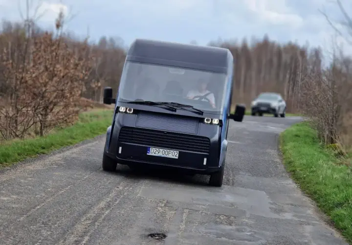 Nowoczesny polski samochód elektryczny przemierza wiejską drogę.