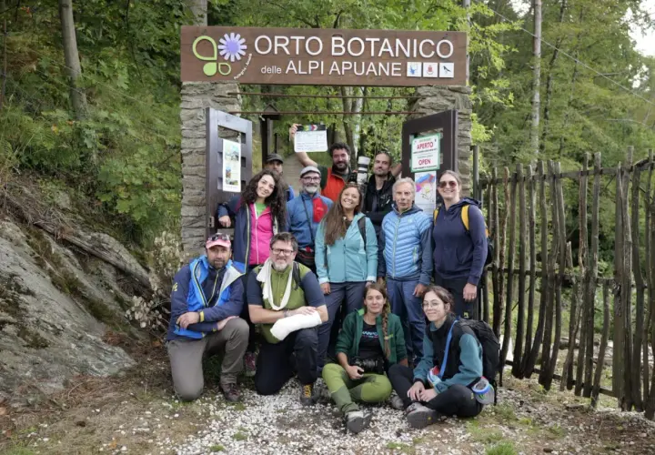 Gruppo di escursionisti posa davanti all'Orto Botanico delle Alpi Apuane. Un uomo tiene in mano una ciak.
