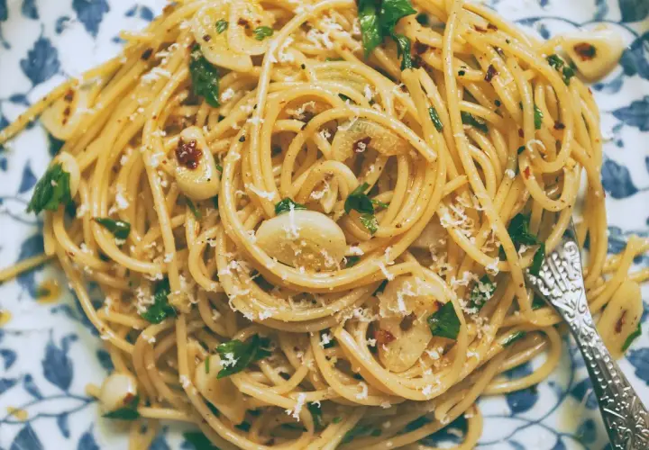 Pyszny makaron aglio olio z czosnkiem, natką pietruszki i płatkami chili, posypany parmezanem.