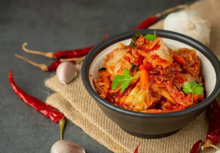 Miseczka z kimchi, obok suszone papryczki chili i czosnek.