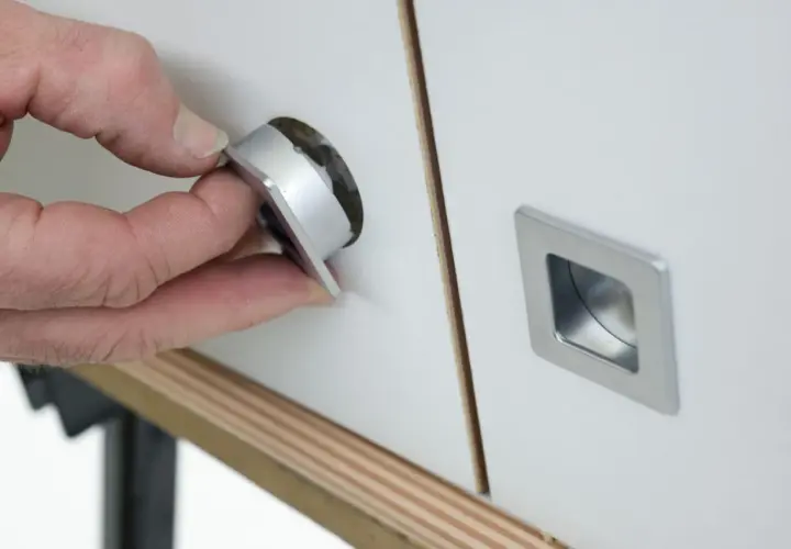 Mano insertando un tirador moderno en un mueble, renovando su aspecto. Ideal para cambiar tiradores mueble antiguo.