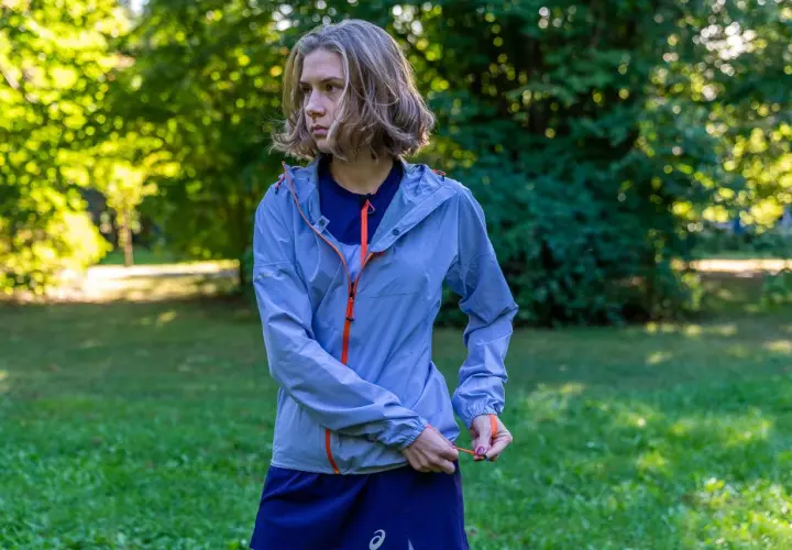 Kobieta w niebieskiej kurtce sportowej z pomarańczowymi zamkami. Taka membrana 10000 co to znaczy? To dobra ochrona przed deszczem i wiatrem podczas biegania.