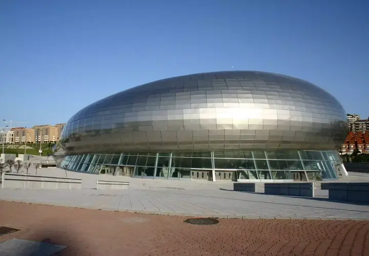El moderno Palacio de Deportes Santander, con su diseño futurista y su cubierta plateada, se alza bajo un cielo azul.