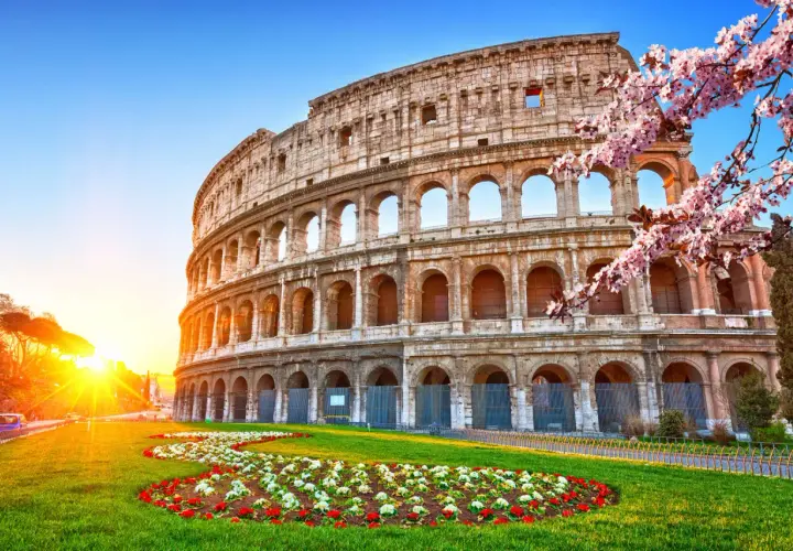 Colosseo illuminato dal sole, con fiori primaverili. Ideale per un soggiorno di costo metro Roma 2 giorni.