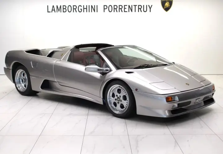 Srebrny kabriolet Lamborghini Diablo z czerwonym wnętrzem, zaparkowany na białej, marmurowej podłodze.