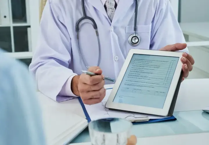 Medico con stetoscopio mostra un modulo su tablet, forse per una nuova unità di degenza.