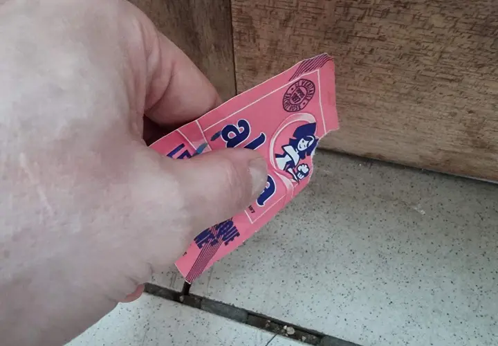Main tenant une étiquette rose, peut-être de levure périmée 1 an, avec une illustration de femme.