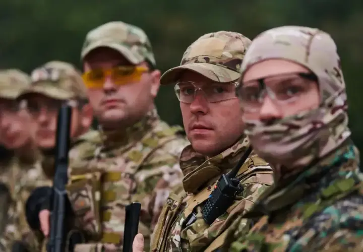 Grupa żołnierzy w kamuflażu, jeden z nich to starszy szeregowy specjalista, gotowi do akcji.