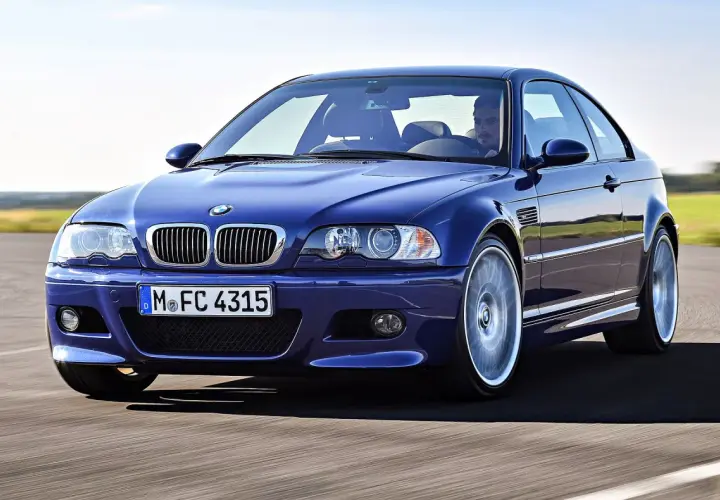 Niebieskie BMW M3 E46, ikona motoryzacji z lat produkcji 2000-2006, pędzi po drodze.