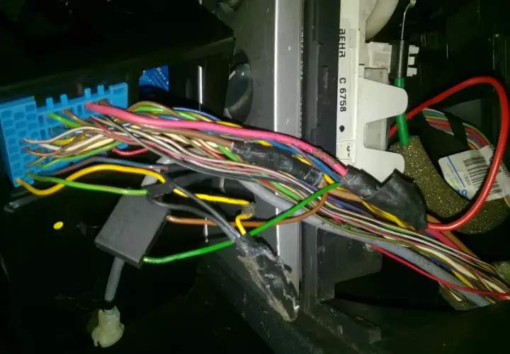 Plątanina przewodów w Opel Meriva, widoczny niebieski konektor i fragmenty instalacji elektrycznej, być może związane z lokalizacją bezpieczników.