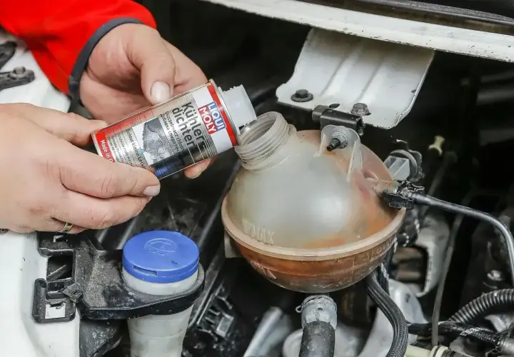 Ręce wlewają Liqui Moly Uszczelniacz chłodnicy do zbiorniczka wyrównawczego.