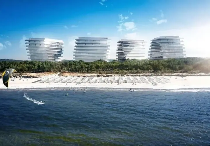 Nowoczesne budynki nad plażą w Międzyzdrojach, gdzie widać kitesurfera na falach.