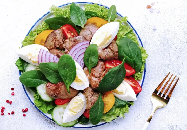 Salade Landaise appétissante avec foies de volaille, œufs durs, tomates, oignons rouges et légumes verts. Quel vin avec une salade landaise ? Un vin blanc sec et fruité.