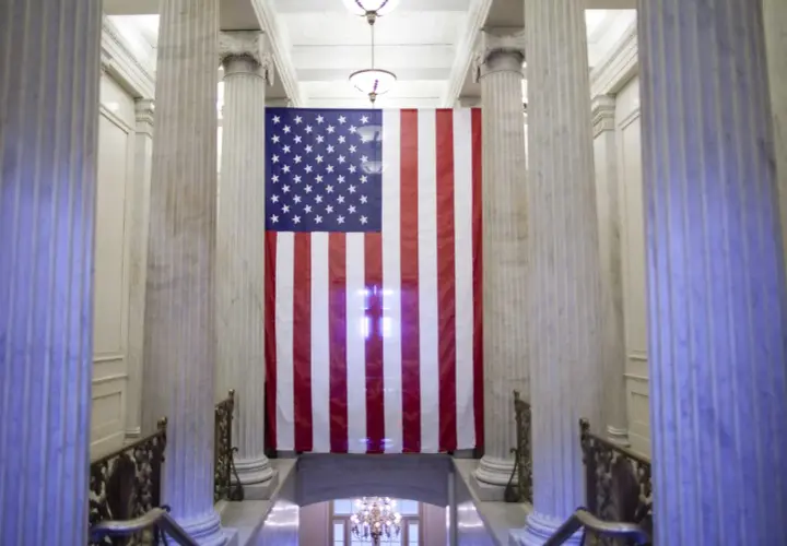 Wielka flaga USA wisi między marmurowymi kolumnami. Czy USA to stany zjednoczone? Tak, to symbol tego kraju.