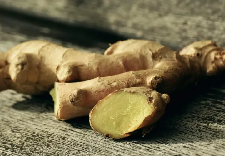 Raíces de jengibre fresco sobre madera, listas para explorar sus usos del jengibre en la cocina, aportando sabor y aroma a tus platos.