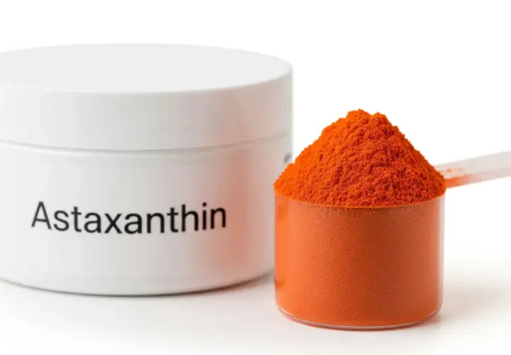 Słoiczek z napisem "Astaxanthin" i miarka pełna pomarańczowego proszku. To właśnie astaksantyna, silny antyoksydant.
