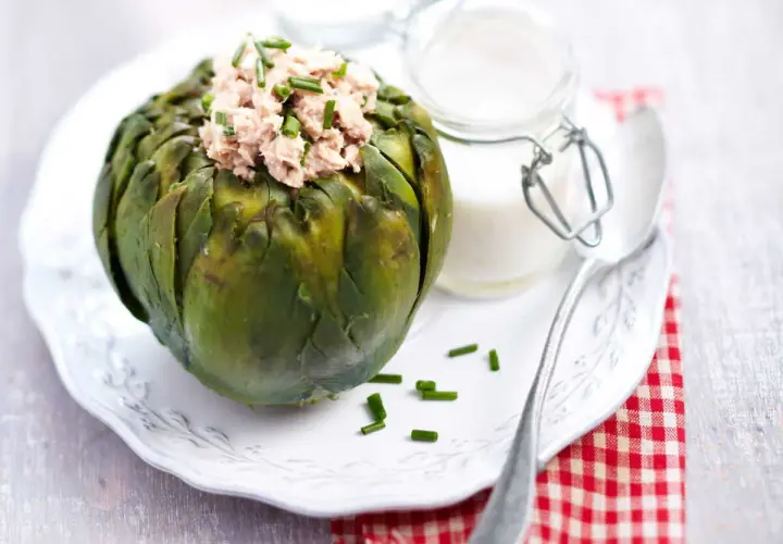 Artichaut farci au thon, garni de ciboulette. Une idée de recette artichaut simple et savoureuse, servie avec une sauce crémeuse.