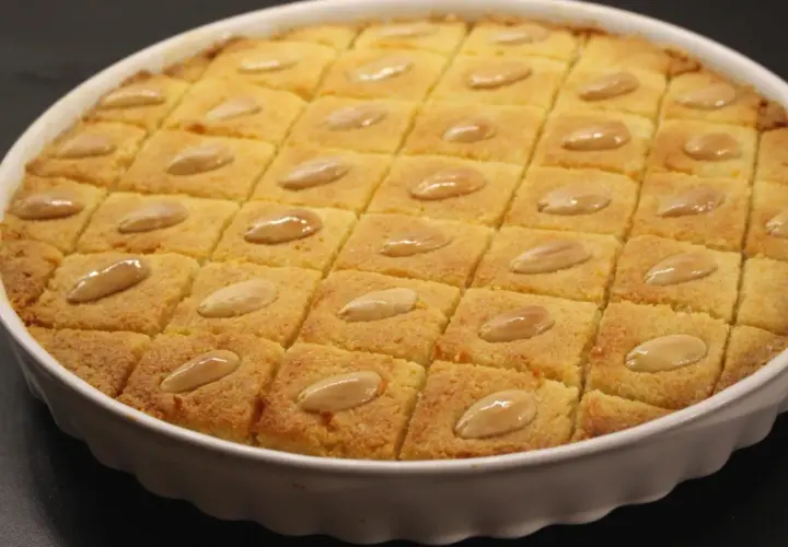 En gyllene basbousa, skuren i rutor och toppad med mandlar. Perfekt för ett enkelt basbousa recept.