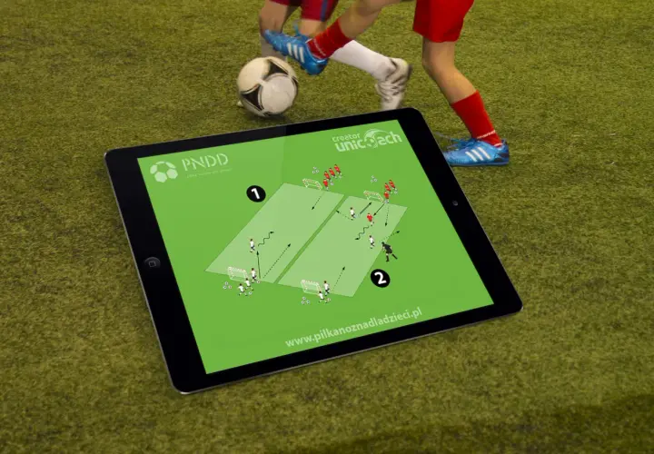 Tablet z planem treningowym do piłki nożnej na 2 osoby. Dzieci ćwiczą na boisku.