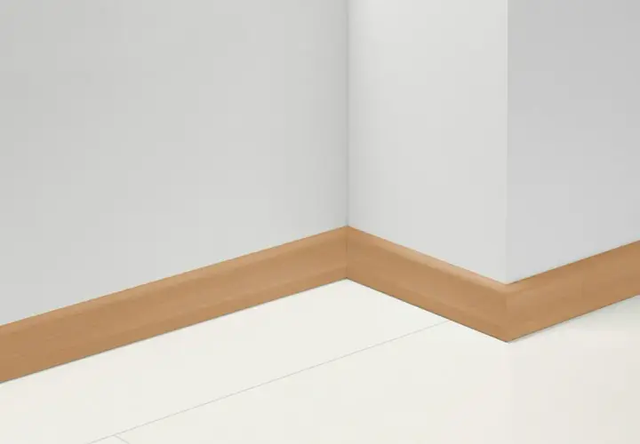 Angolo di una stanza con battiscopa in PVC effetto legno. Impara come tagliare battiscopa PVC per un'installazione perfetta.