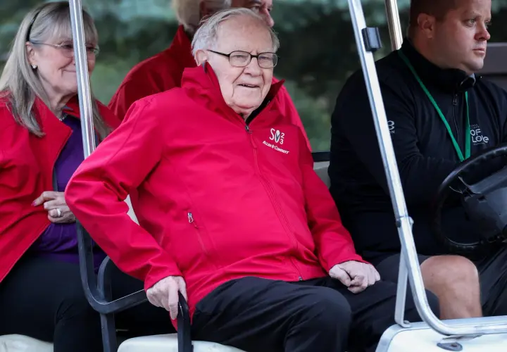Warren Buffett w czerwonej kurtce z logo Allen & Company, siedzi w golfowym wózku.