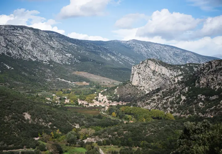 Vue panoramique sur le village de Saint-Guilhem-le-Désert, niché au creux de montagnes rocheuses. Un paysage idéal pour déguster un vin rouge local.