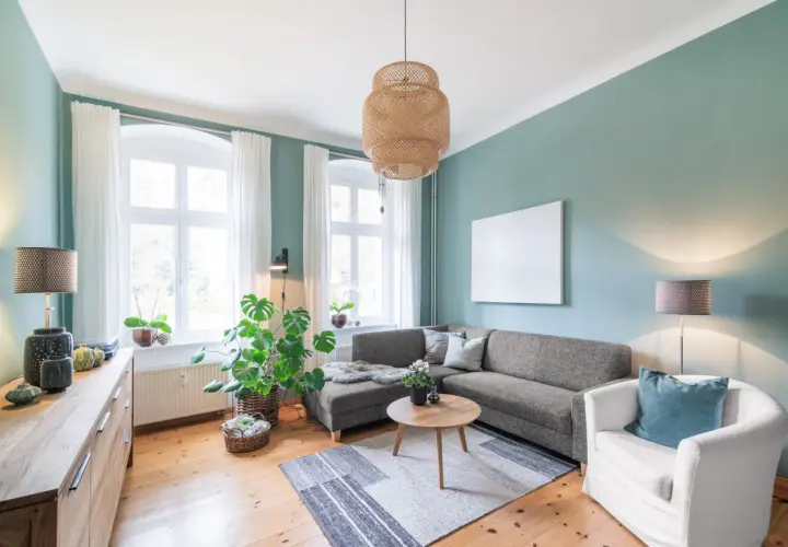 Gemütliches Wohnzimmer mit Sofa, Sessel und Holzboden. Pflanzen und natürliche Materialien schaffen eine harmonische Feng Shui Atmosphäre.