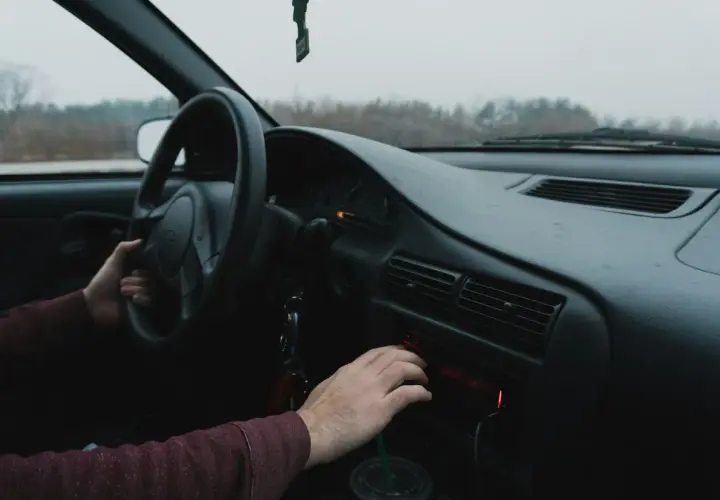 Ręka kierowcy szuka kodu do radia Renault, by włączyć ulubioną muzykę podczas podróży.