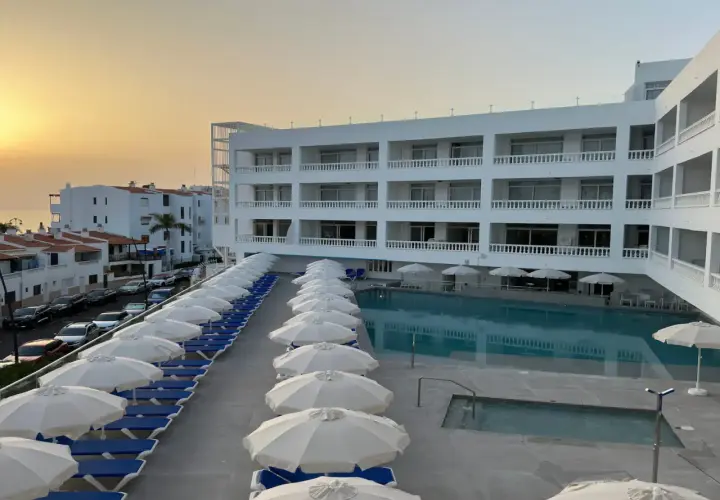 Hotel moderno con piscina y tumbonas, vistas al mar y al atardecer. El azul mar de Lagos de César invita al descanso.