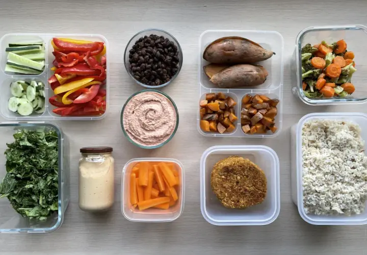 Healthy Japanese bento box ideas for adults: rice, veggie patties, roasted sweet potatoes, carrots, hummus, black beans, and fresh greens.