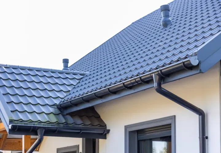 Szary dach z dachówki ceramicznej, idealny do obliczenia dachówka ceramiczna cena za m2. System rynnowy odprowadza wodę.