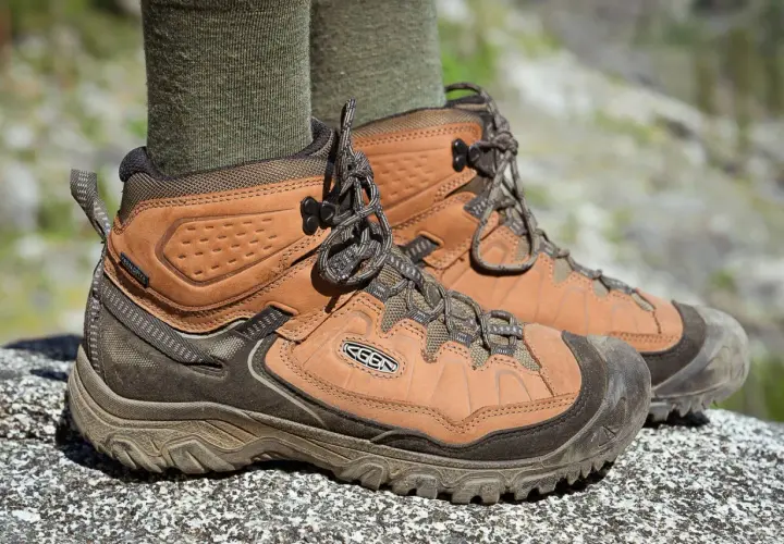 Brown leather hiking boots with green socks. They fit snugly, offering support for any trail.