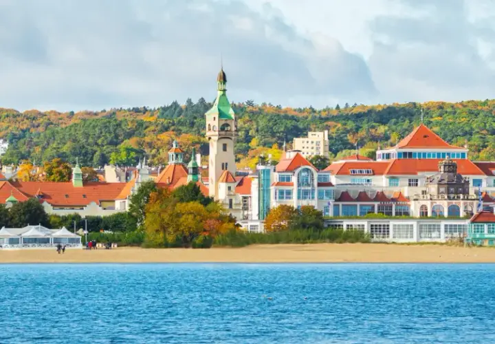Malownicze widoki na plażę i zabytkowe budynki w Sopocie. Zobacz słynną latarnię morską i kościół na tle jesiennych drzew.