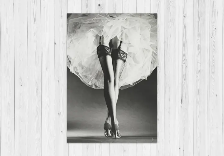 Nogi w pończochach i szpilkach, ukryte pod zwiewną spódnicą. Klasyka w stylu Horst P. Horst.