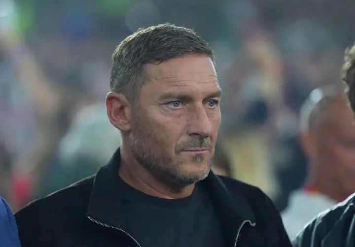 Francesco Totti, legenda piłkarzy z Rzymu, w czarnej kurtce, z uwagą obserwuje wydarzenia.