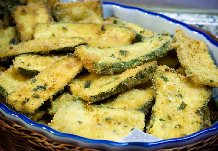 Zucchine gratinate in padella, dorate e croccanti, servite in un cestino di vimini.