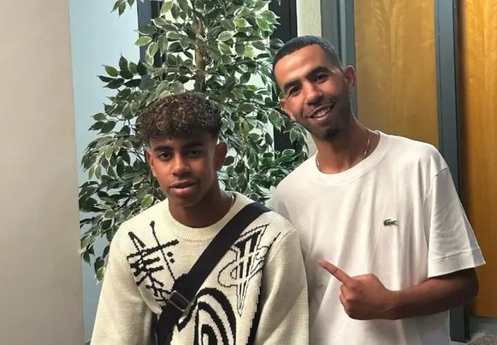 Mounir Nasraoui z młodym chłopcem pozują do zdjęcia obok sztucznej rośliny.