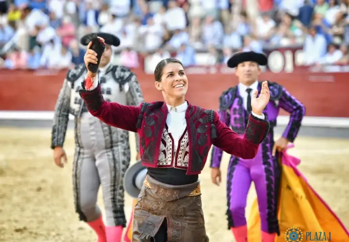 Mujeres de toreros famosos, con trajes de luces, saludan al público en la plaza de toros.