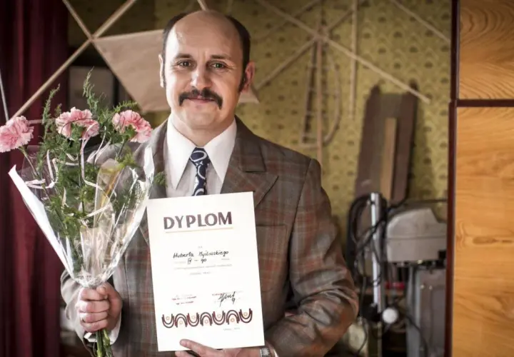Adam Woronowicz z bukietem i dyplomem, jakby po premierze jednego z jego filmów.