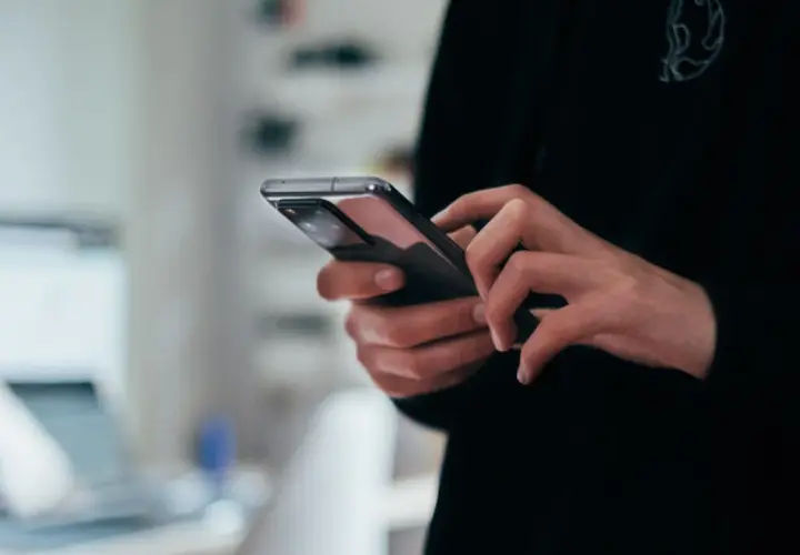 Dłonie trzymające nowoczesny smartfon, widok z bliska.
