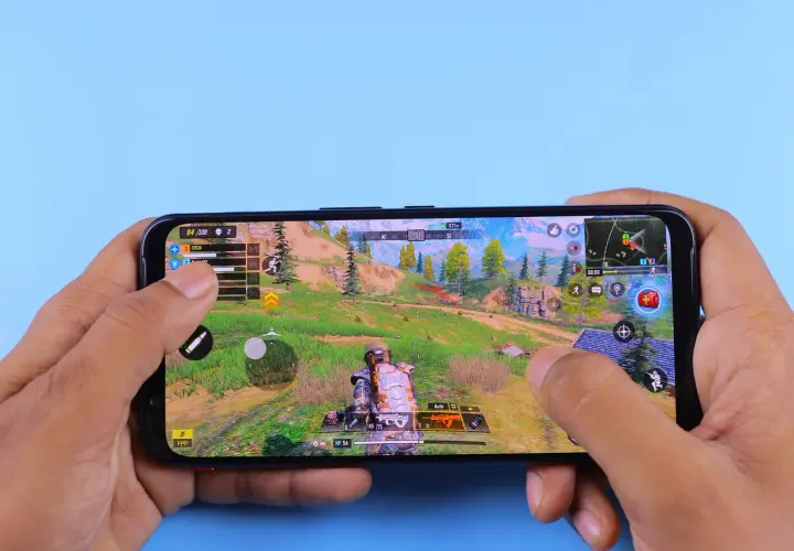 Ręce trzymają smartfon, na którym widać dynamiczną rozgrywkę z jednej z najlepszych gier android. Akcja toczy się w malowniczej, górskiej scenerii.