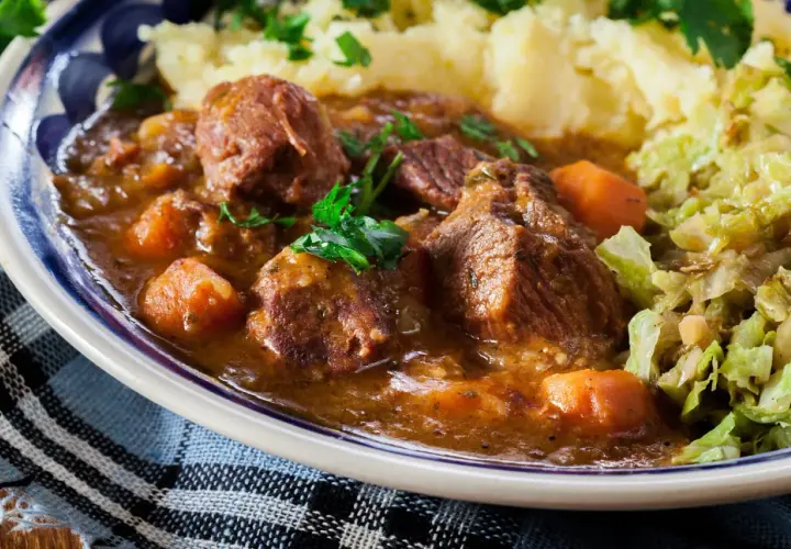 Un plat réconfortant de navarin d'agneau, avec des morceaux de viande tendres, des carottes et une sauce savoureuse, servi avec de la purée et du chou. Une recette parfaite pour un repas familial.
