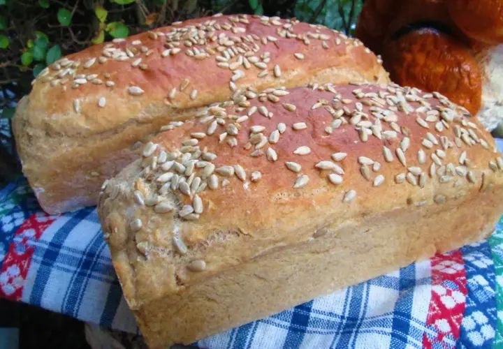 Dwa bochenki domowego chleba posypane słonecznikiem, idealne do nauki jak upiec chleb w domu.