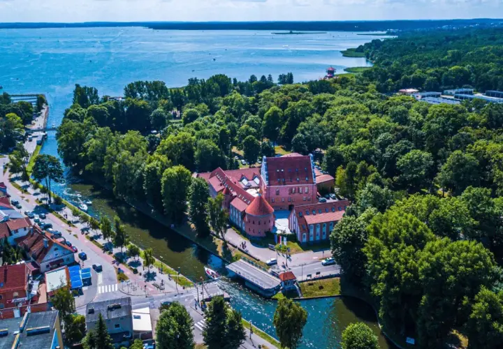 Malowniczy hotel na Mazurach, otoczony zielenią i wodą, z widokiem na jezioro. Idealne miejsce na wypoczynek.