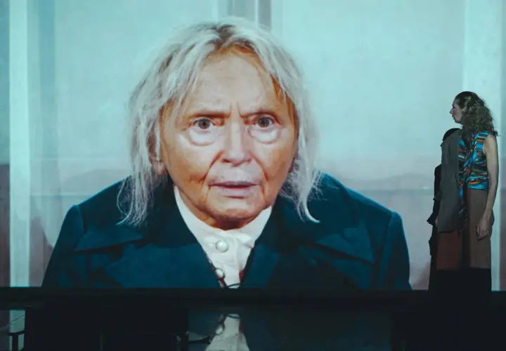 Na ekranie twarz starszej kobiety, w tle młoda kobieta. To scena z przedstawienia "święta Liliana".