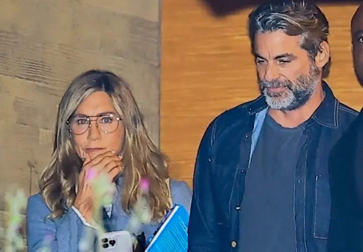 Jennifer Aniston z partnerem, w okularach, z telefonem i książką w ręku, obok mężczyzny z siwą brodą.