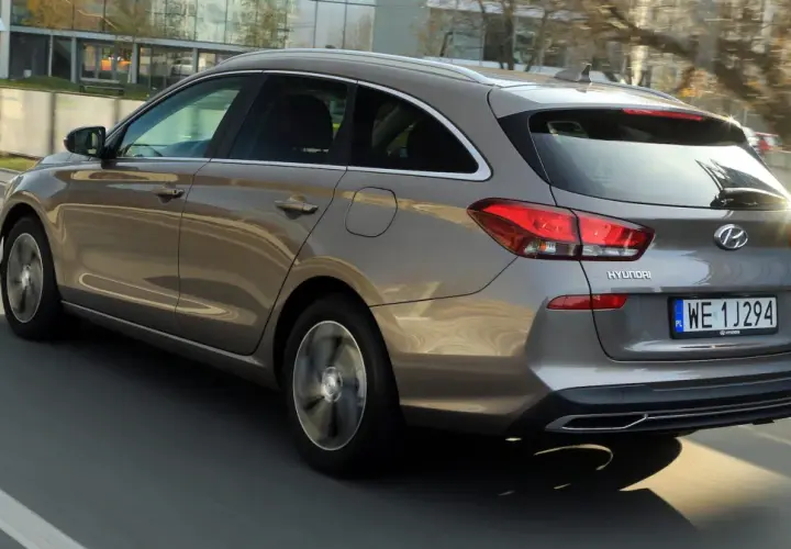 Szary Hyundai i30 1.6 CRDi kombi jedzie po drodze, widać jego tylną część i bok.