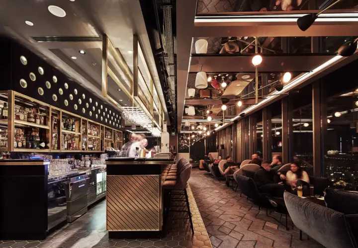Elegancki bar i wygodne fotele tworzą klimatyczne restauracje Katowice. Goście relaksują się przy widoku na nocne miasto.