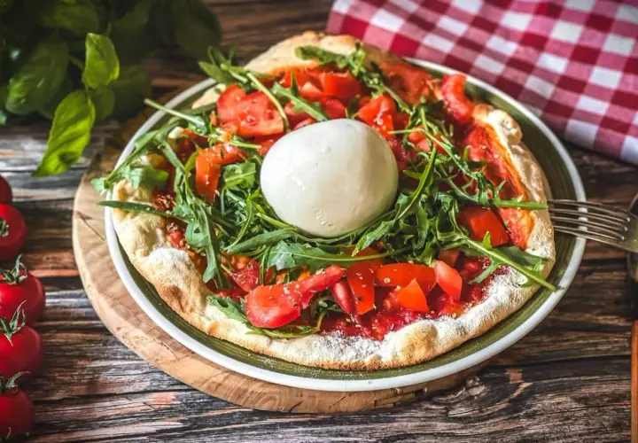 Pizza mit frischen Tomaten, Rucola und einer Kugel Burrata, die Lust auf burrata selber machen macht.